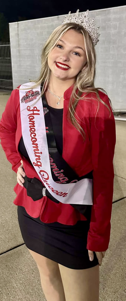 Payton Walker 2026-2027 Homecoming Queen.  She is standing in front of a brick wall showing off her crown.  