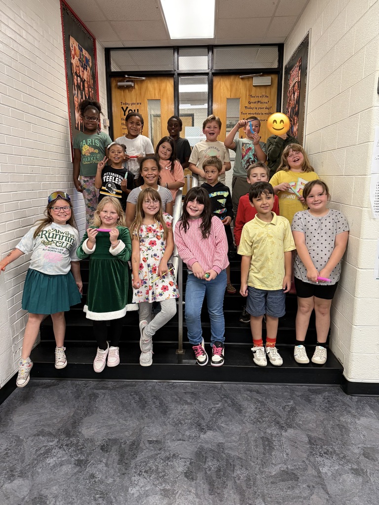 Group of students, varying in age, pose for a photo on a staircase inside a building.