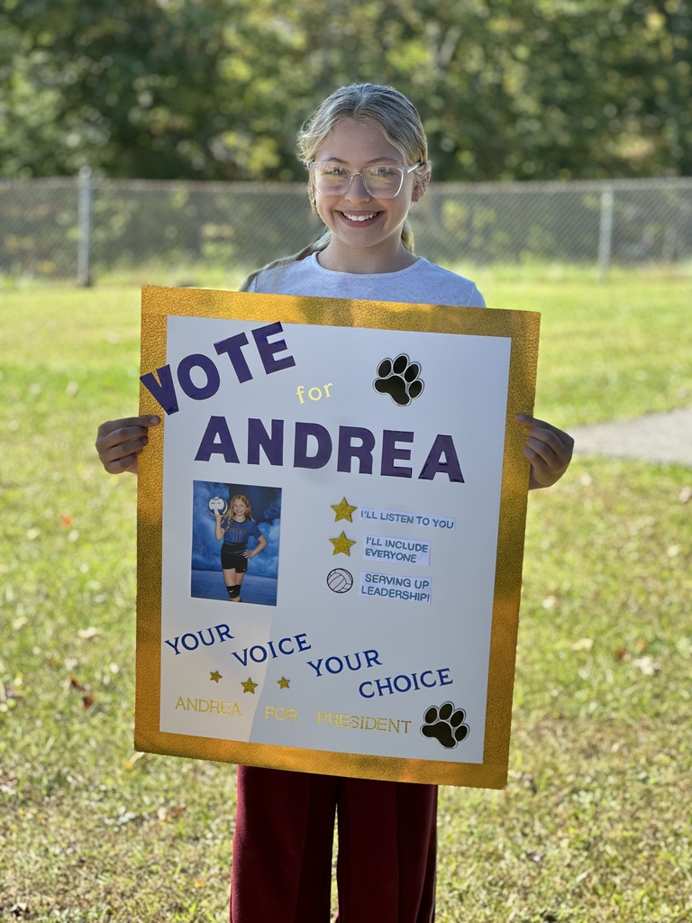 A child holds a colorful sign with a photo of a girl in a blue uniform.