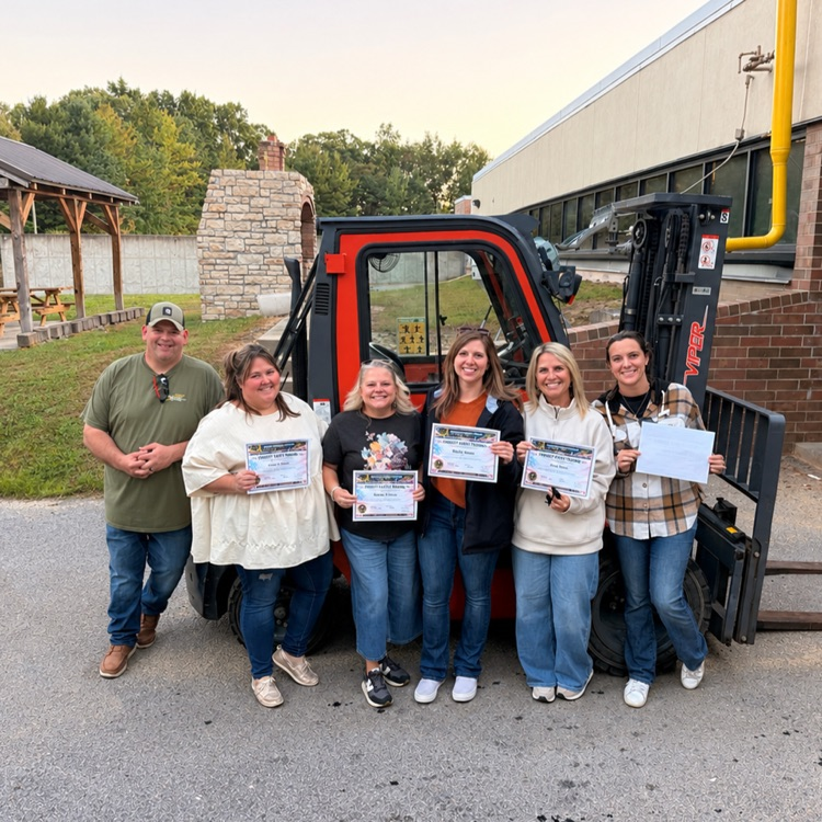 five people standing in front of a red forklift holding certificates