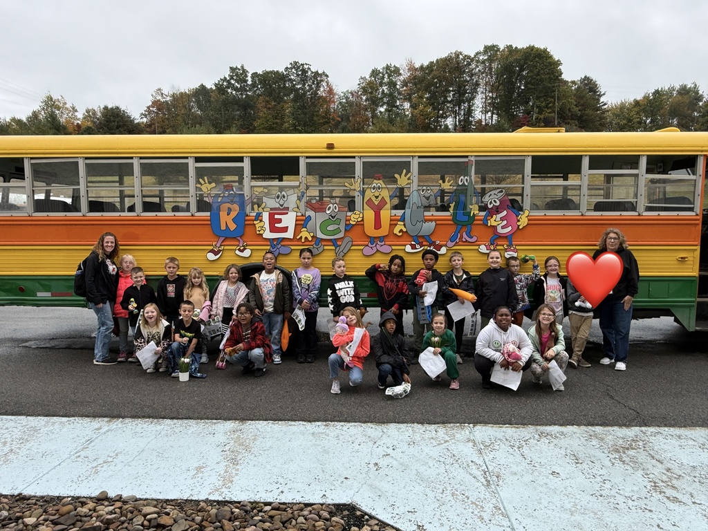 A group of students and adults standing in front of a colorful school bus with RECYCLE letters.