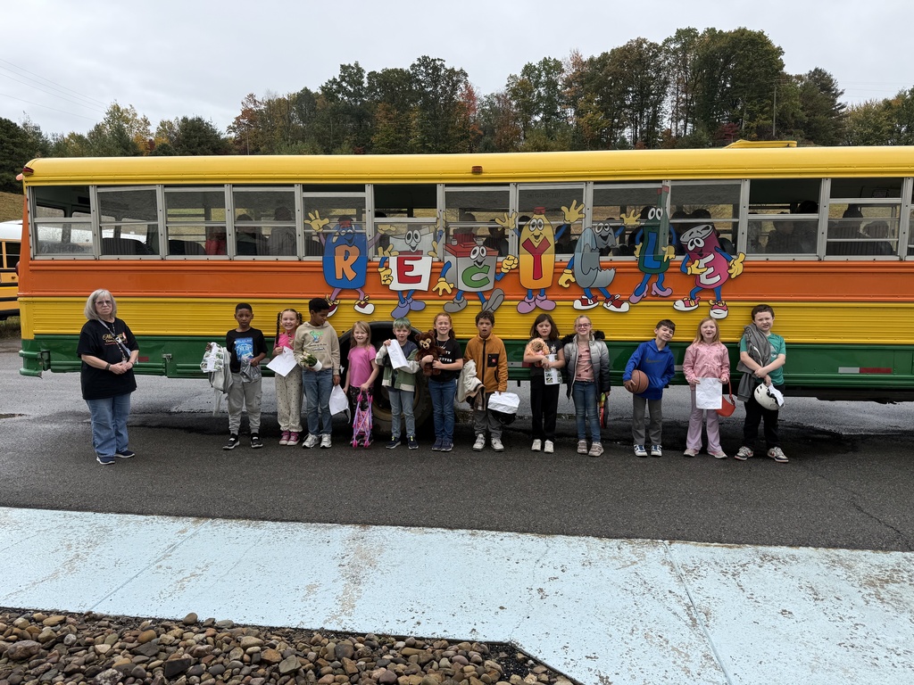 Students line up outside next to a bus with colorful artwork and letters on the side.