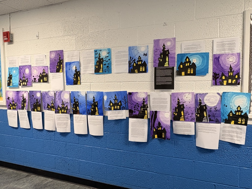 Display of artwork on a blue wall with a white border, featuring a variety of colorful paintings.