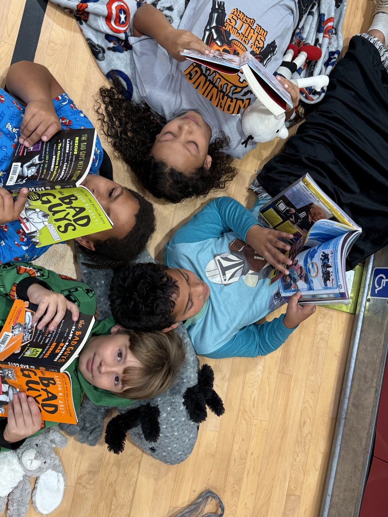 Four children on a floor, each holding a book. One child wearing a blue shirt holds a book titled "Bad Boys."