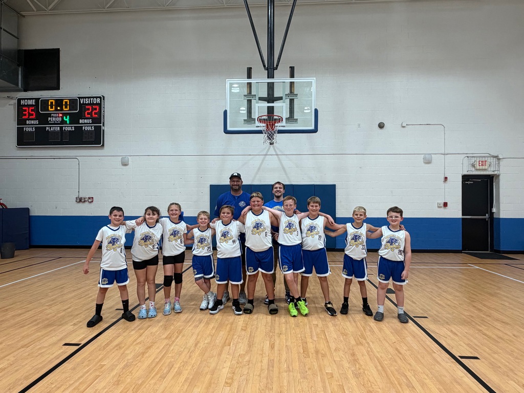 A group of students in blue and white uniforms standing together on a basketball court.