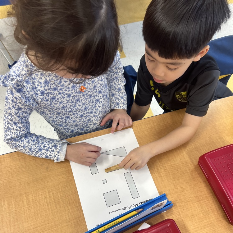 Kindergarten friends working together in partners to find matching faces with our geoblocks—teamwork and problem-solving in action!