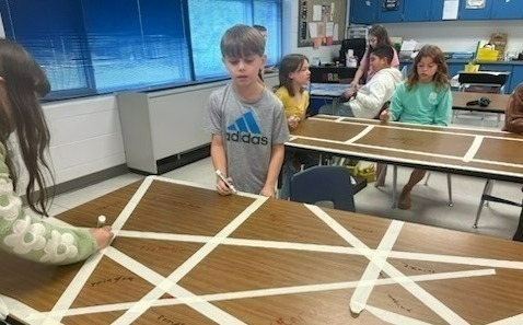 Mrs. Hunt's fourth grade students creating any design with tape on their desk as a canvas.