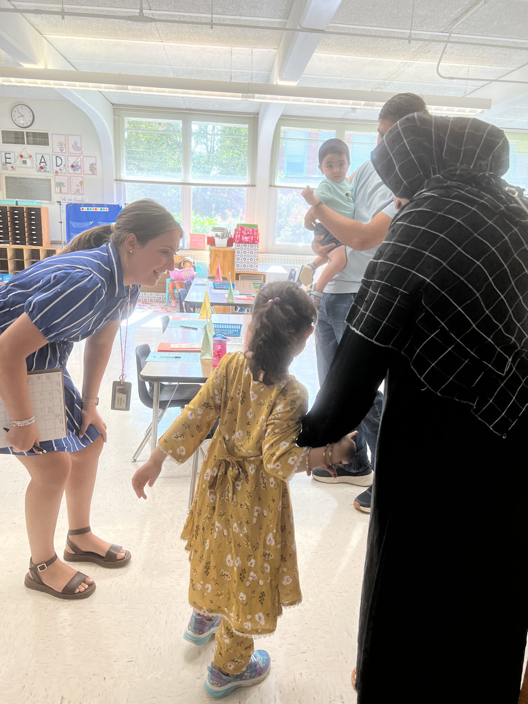 A teacher talking to a student and parent in a classroom