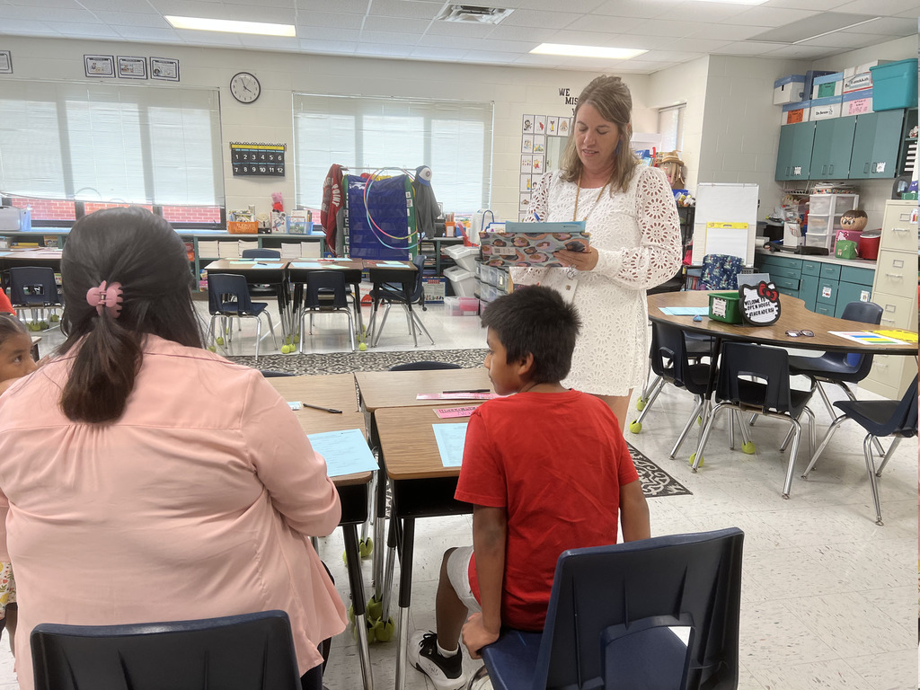 A teacher talking to a student and parent in a classroom