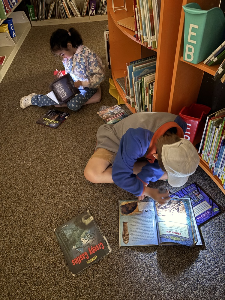 Children reading in a dark media center with flashlights.