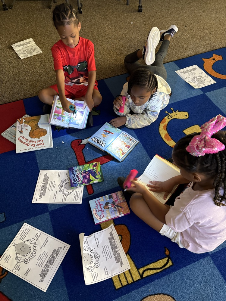 Children reading in a dark media center with flashlights.