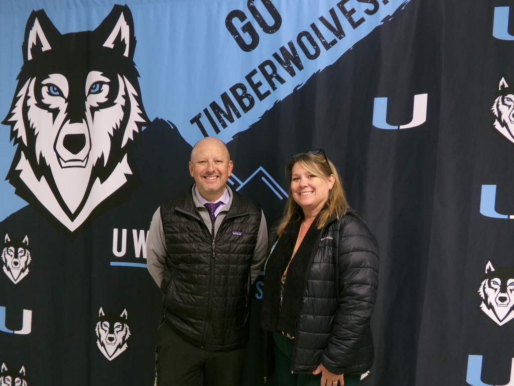 Two people standing in front of a Wolf banner