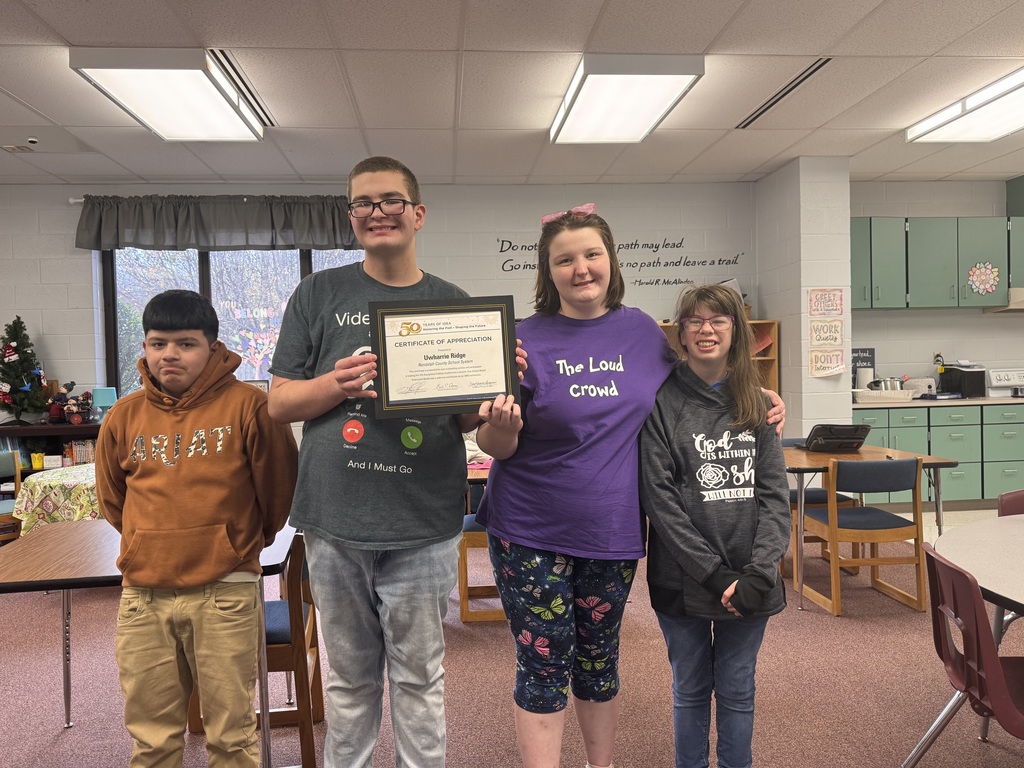 Students in a classroom with a certificate. 