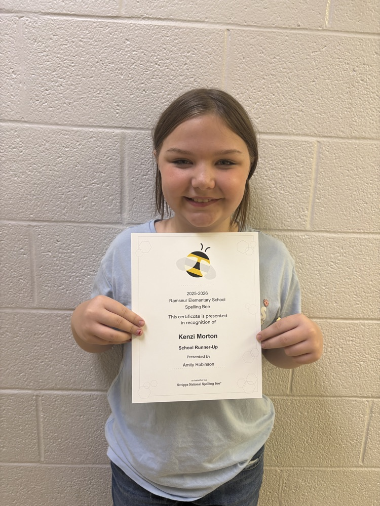 student holding a certificate that says spelling bee runner up