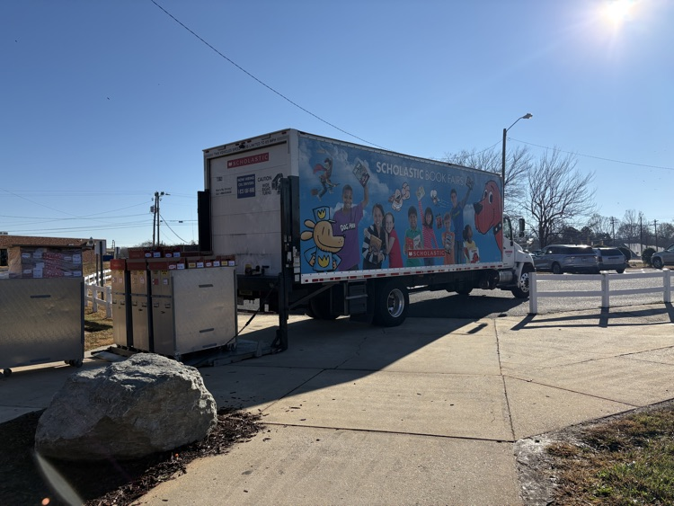 book fair truck with book characters in school parking lot.