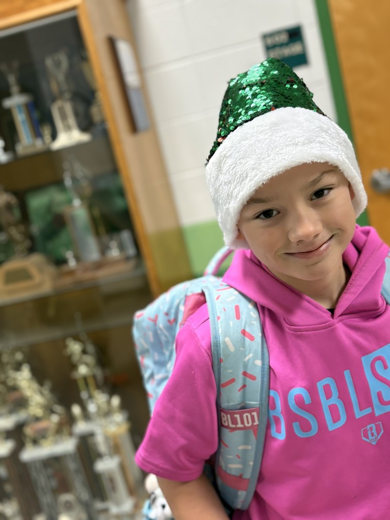 A student in the hallway wearing a green sequin Santa hat.