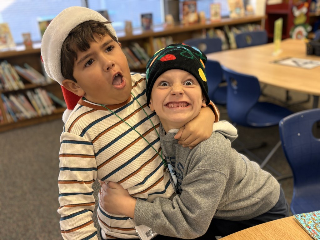 Two students in the library in their holiday hats.
