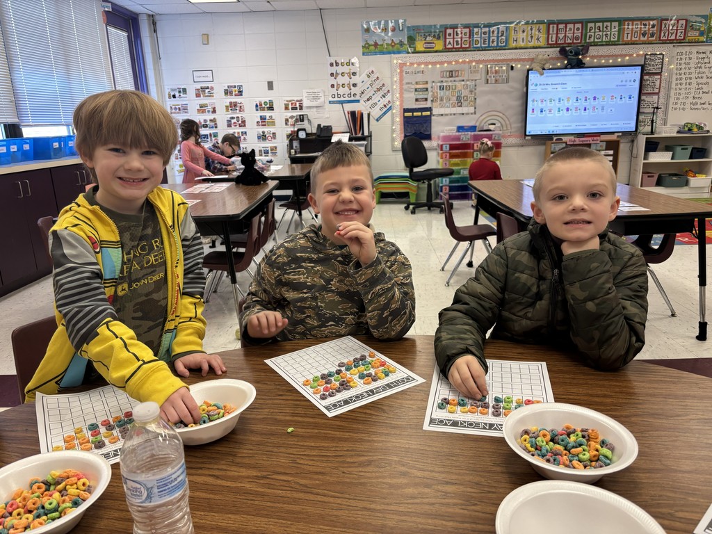 Three kindergarten students working on 100th day activities in their classroom.