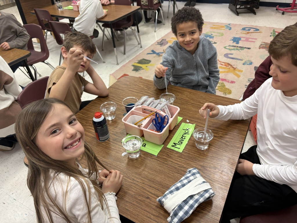 Students performing science experiments with water, food dye and shaving cream.