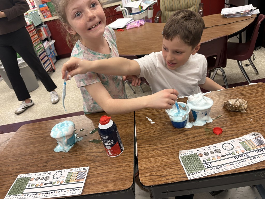 Students performing experiments with shaving cream, water and food dye.