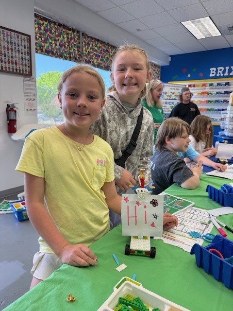 5th grade girls showing off a sign they made at Brick Ed.