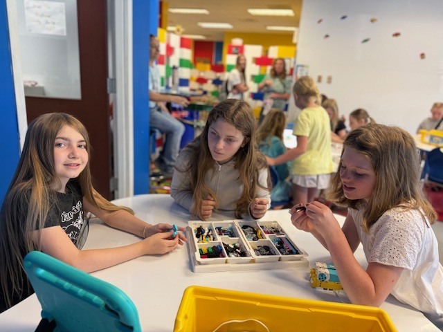 5th grade girls creating items with Legos at Brick Ed.