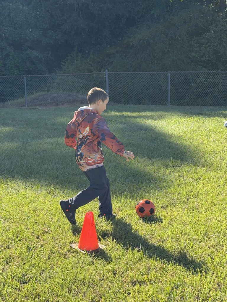 A student kicking a soccer ball.