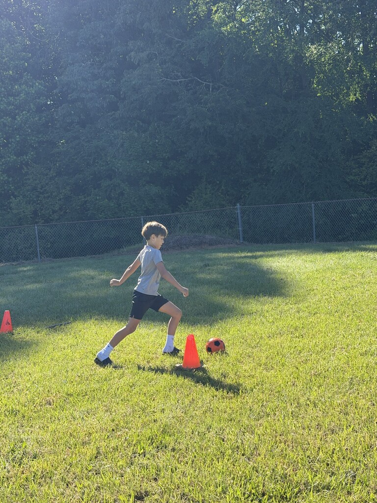 A student kicking a soccer ball.