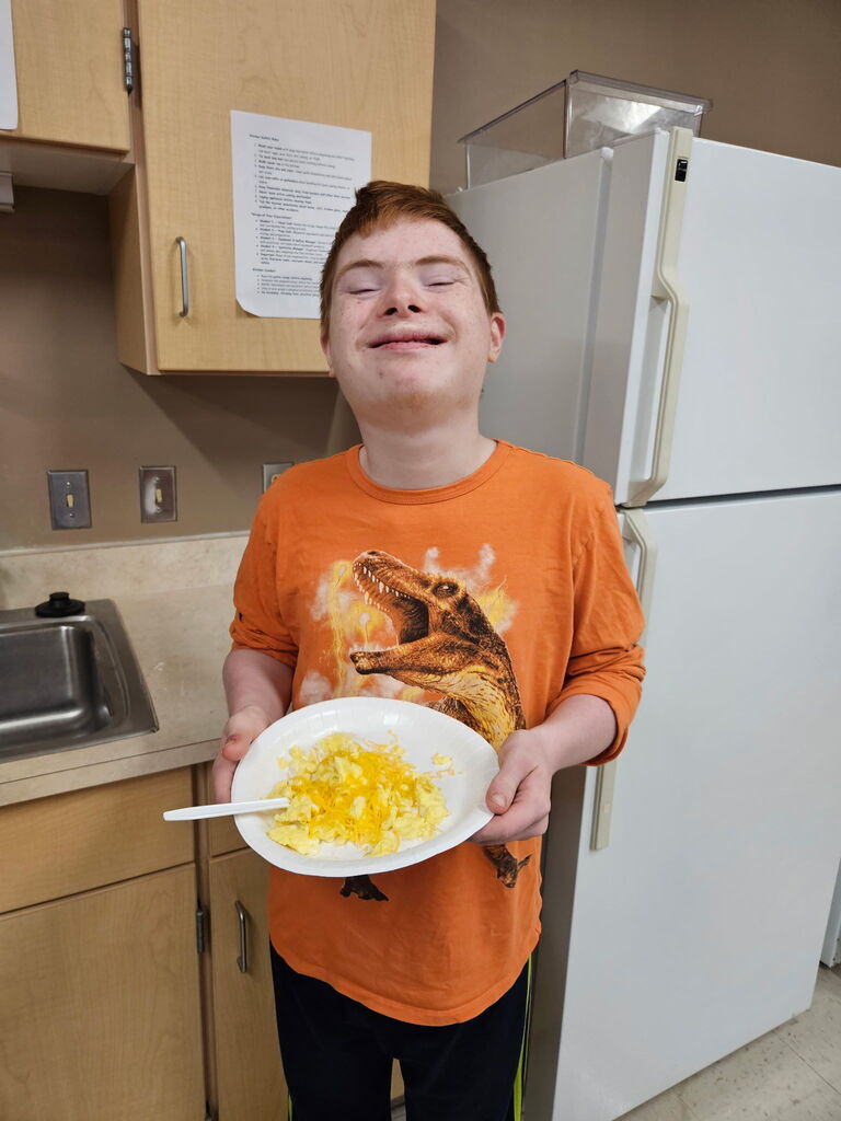Happy student holding plate of scrambled eggs