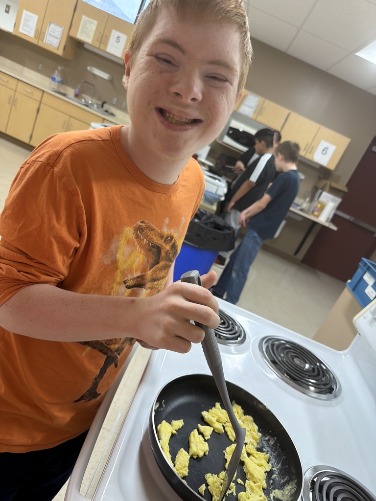 Joyful student cooking eggs on a stove