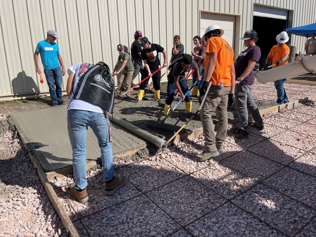 students helping pour concrete 