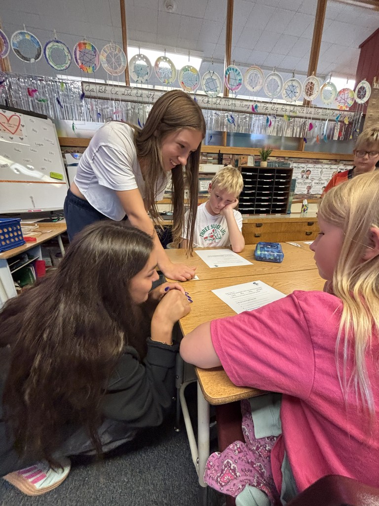 high school students helping elementary students