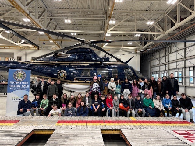 Group of students posing with a helicopter