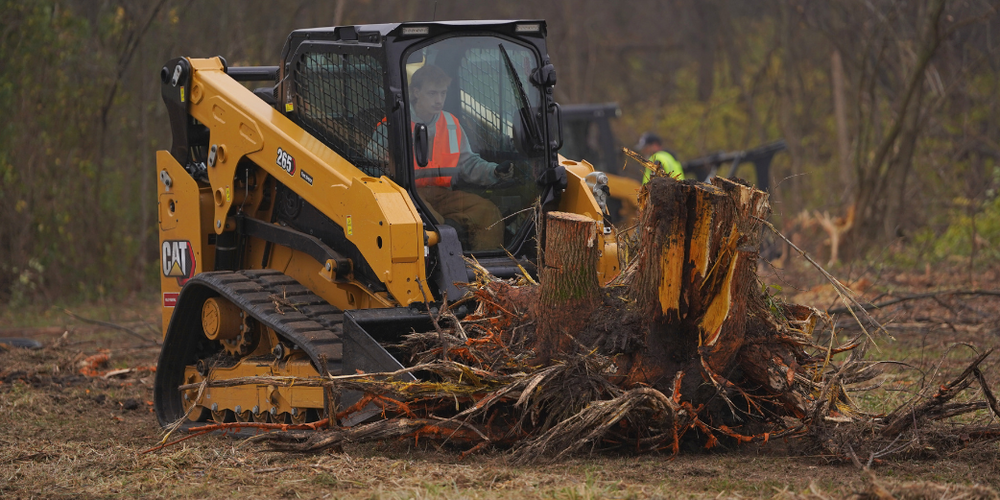 Students clearing tree in heavy machinery