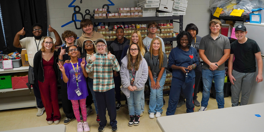 A group of students pose for a picture in a pantry