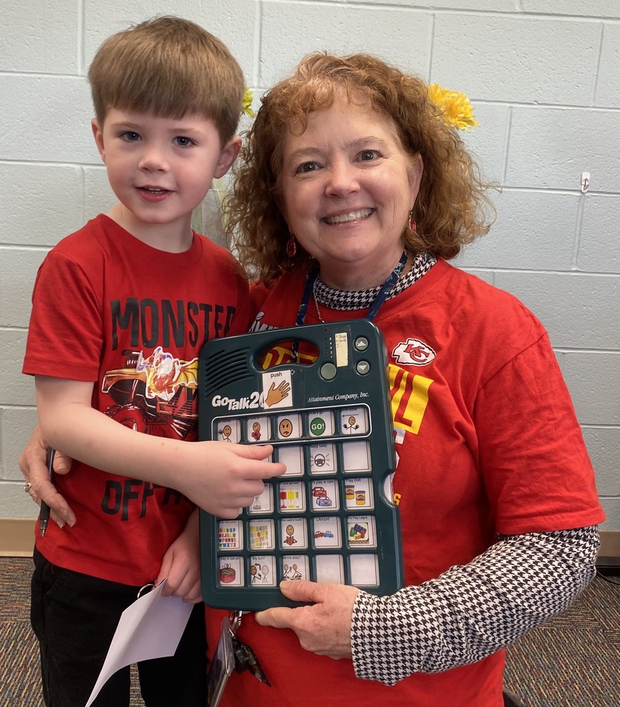 Child and teacher holding a communication device and award certificate
