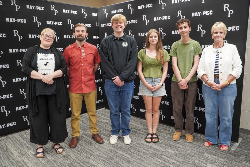 A group of people smile in front of a black RP branded backdrop