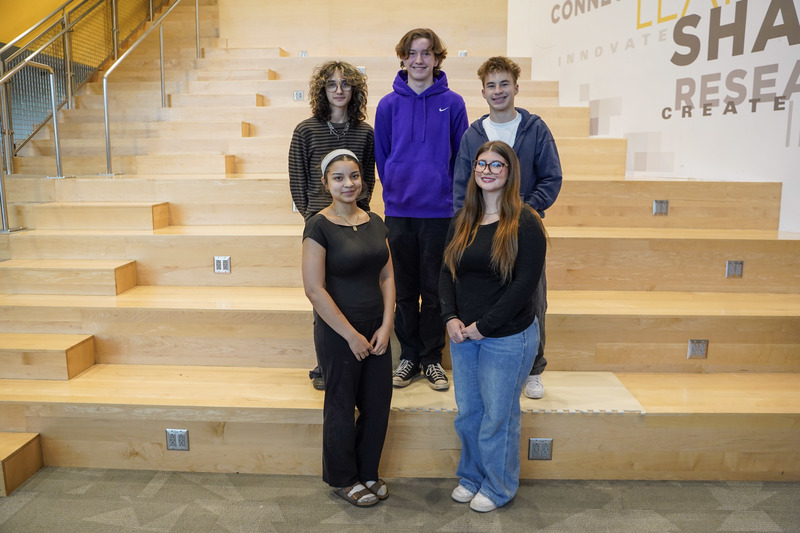 A group of students standing on a staircase. The girls are standing in front and the boys and standing behind the girls.