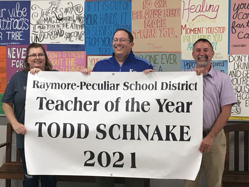The people holding a banner for the 2021 Teacher of the Year
