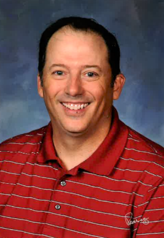 A man with brown hair and a red striped shirt smiles