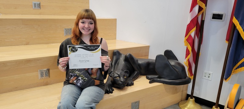 Student smiling and posing with certificate next to a panther