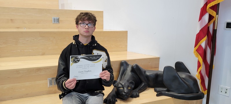 Student smiling and posing with certificate next to a panther