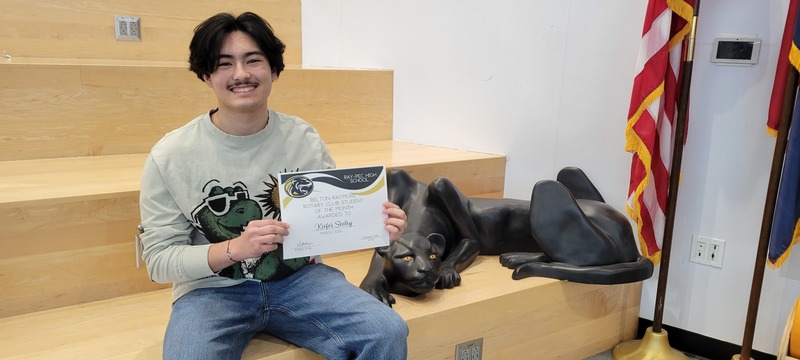 Student smiling and posing with certificate next to a panther