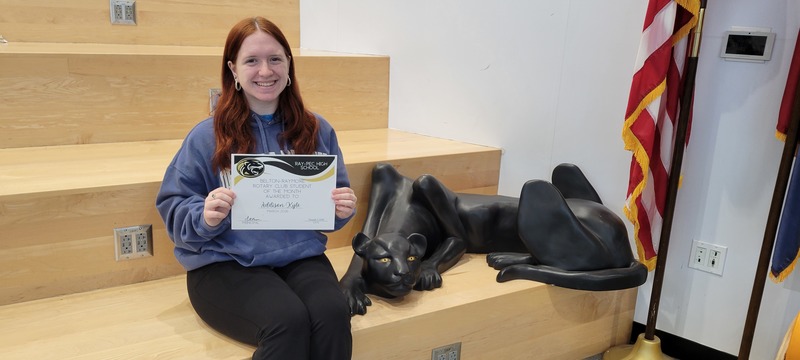 Student smiling and posing with certificate next to a panther