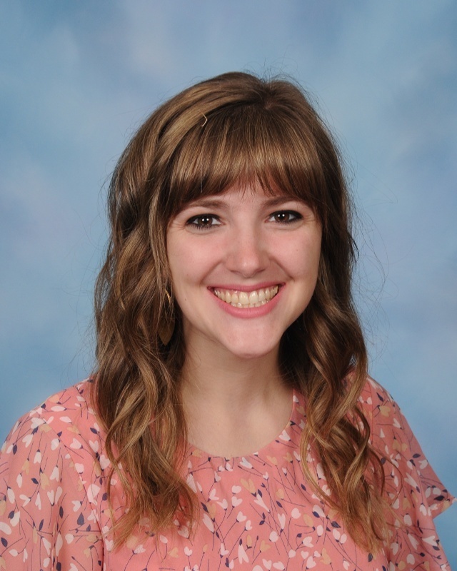 A woman in a pink shirt smiling with her hair down
