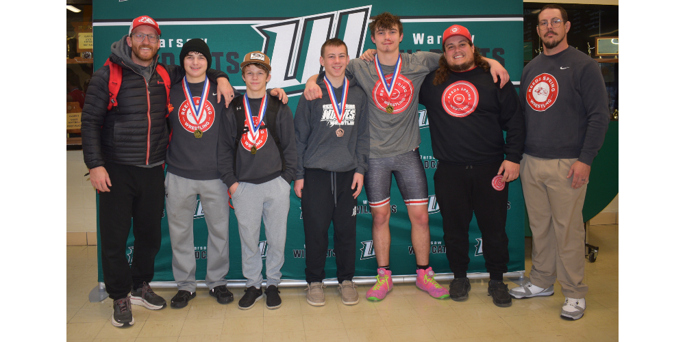 4 wrestlers and three coaches pose with medals