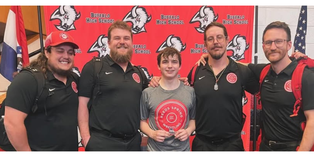 wrestler in middle with 2 coaches on right and two on left