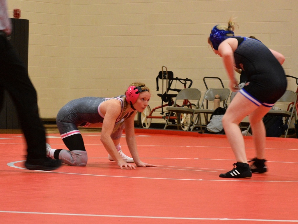 female wrestler on knees looking at opponent