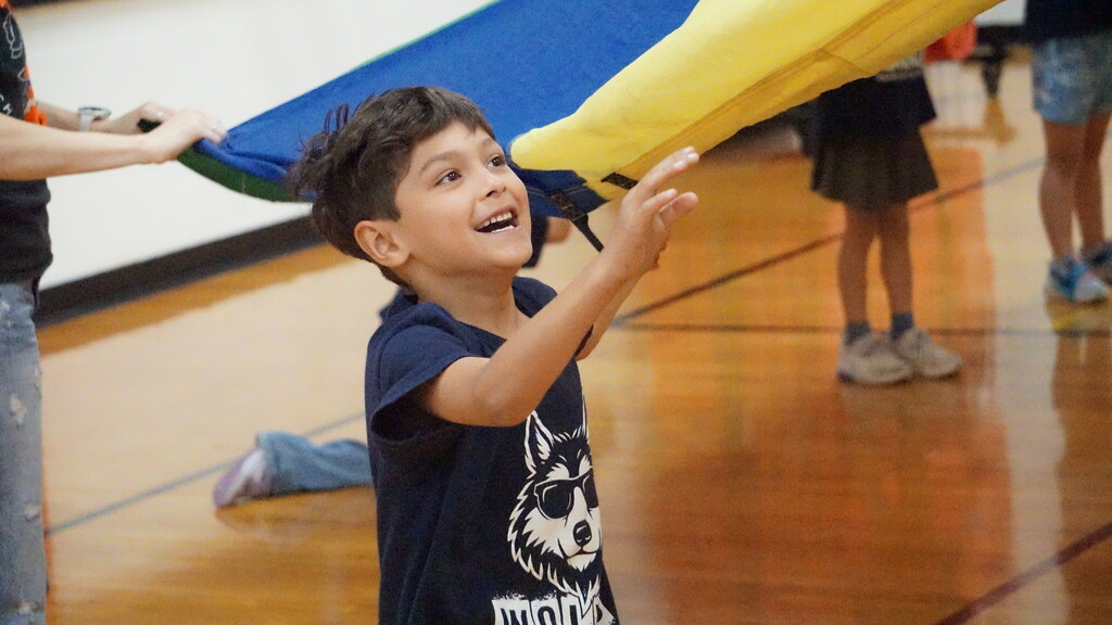boy smiling while playing with a parachute