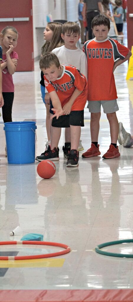 boy rolling ball towards hula hoop